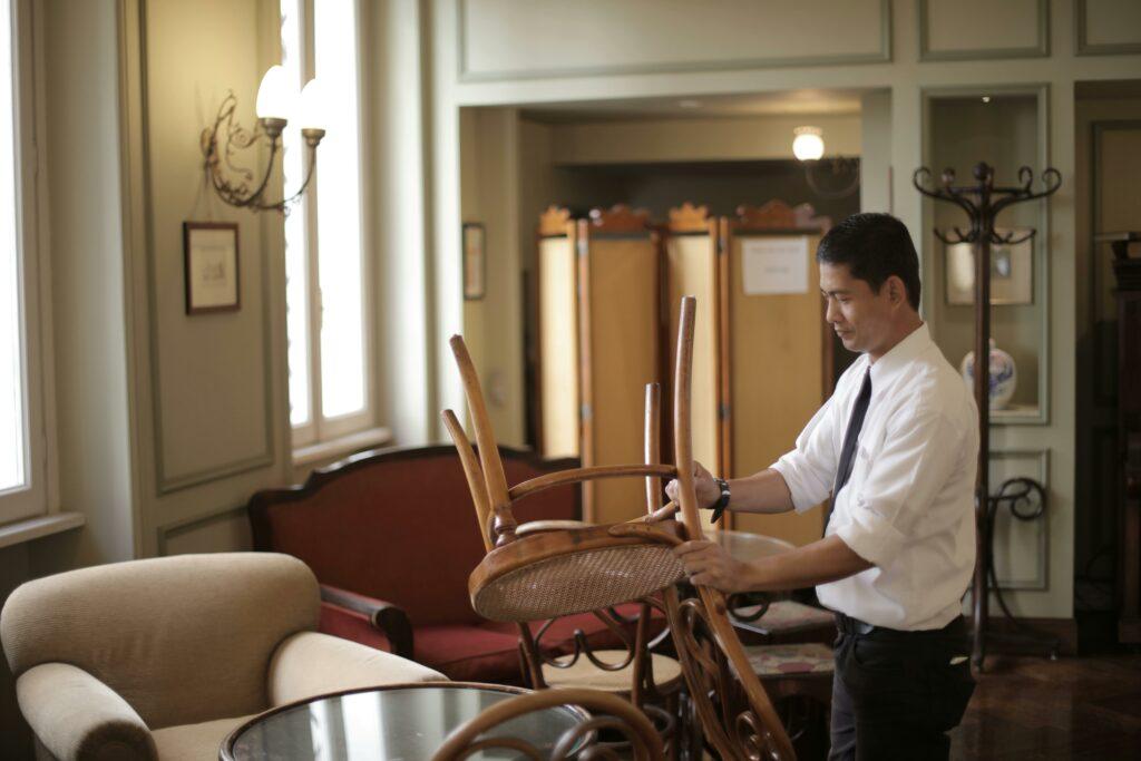 A restaurant manager puts chairs up onto tables at the end of the day.